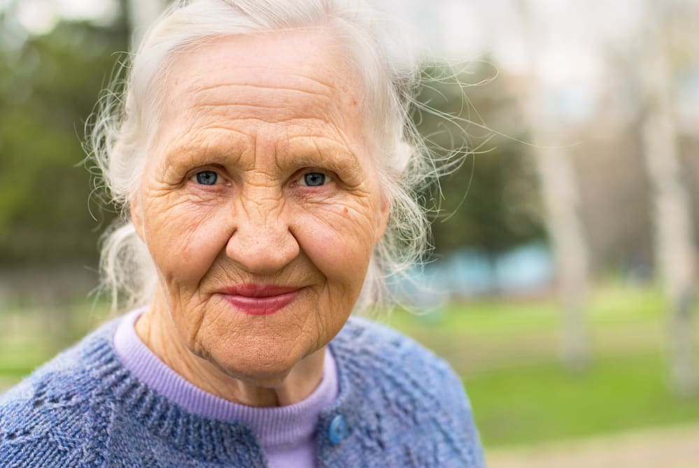 Close-up of senior woman smiling, outdoor background